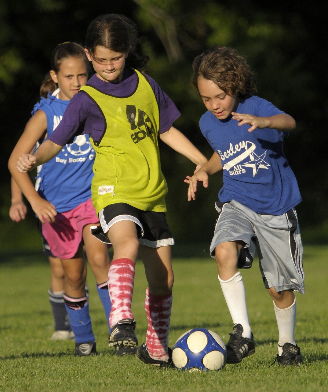 Two soccer players, a boy and girl, challenge for the ball