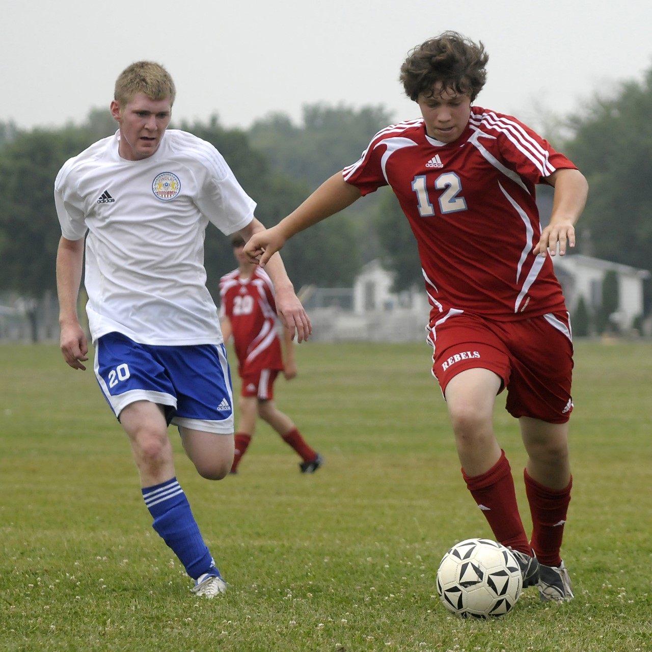Two male high school soccer players challenge for the ball