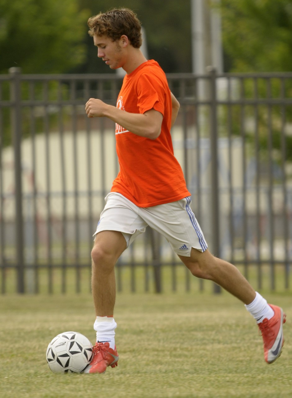 A male soccer player dribbles a soccer ball